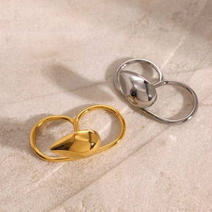 Close-up of gold and silver minimalist water drop double rings on a stone base