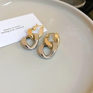 Détails de boucles d'oreilles bicolores or et argent sur un plateau en céramique élégant