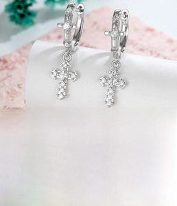 Vue macro de boucles d'oreilles croix en argent avec zircons et base en cuivre