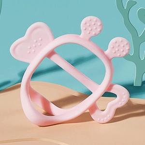 Pink silicone baby teether with massaging texture on a clean decorative background