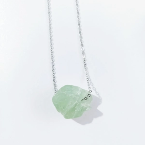 Detailed view of large raw green crystal pendant with silver delicate chain necklace