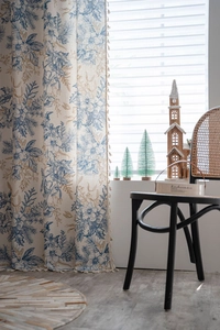 Detail of pine branch print curtain with beige tassels in a cozy home setting