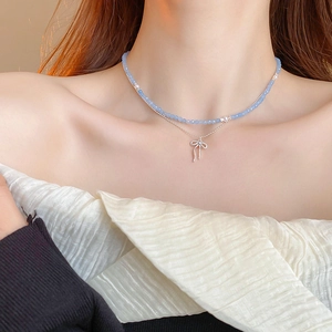 Close-up of double-layer necklace featuring blue beads and silver butterfly pendant