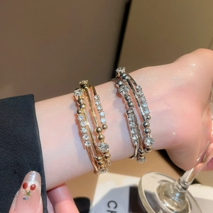 Detail of layered geometric bracelet with rhinestones in gold and silver finish