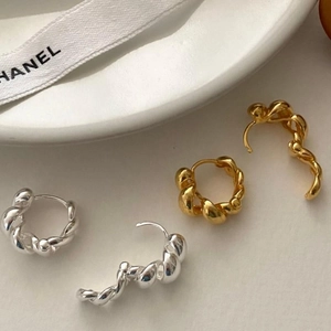 Detail shot of twisted rope hoop earrings in gold and silver finish on white tray