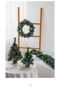 Close-up of mini PE Christmas trees and pine needle wreath with snowy finish and pine cones