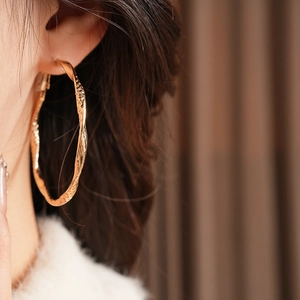 Detail of vintage gold hoop earrings with hammered texture worn by a model in profile view