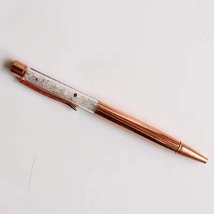 Macro view of rose gold crystal pen filled with black and clear quartz stones