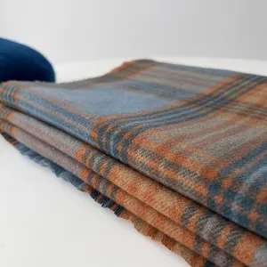 Detailed macro view of orange and blue plaid scarf fabric texture with soft tassels
