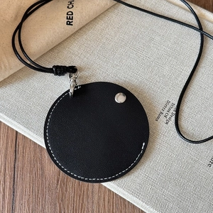 Detail of black faux leather magnetic glasses holder necklace on natural book background