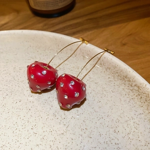 Close-up of red resin strawberry earrings with sparkling rhinestones and gold hooks