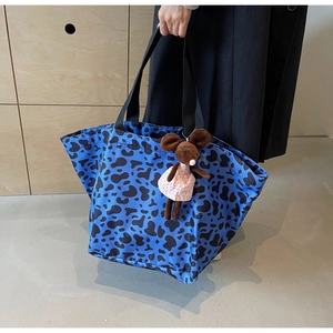 Detail of blue animal print tote bag with black strap and mouse plush pendant