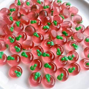 Close-up of mini 3D translucent red resin apples with green leaves on white plate