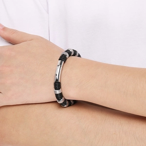 Macro detail of men's stainless steel woven leather bracelet with textured metal links