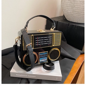 Detail of vintage radio acrylic bag showing golden metal dials and polished black finish