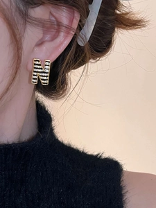 Detailed close-up of 18K gold plated letter N stud earring with black stripes and zircons