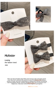 Detailed close-up of bow-shaped hair clips with grey rhinestones and black clips