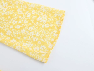 Close-up of yellow floral fabric with white print on French tea break dress cuff