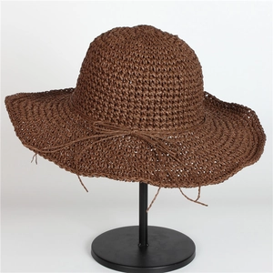 Dettaglio di un cappello di paglia intrecciato marrone con fiocco sottile e trama fitta
