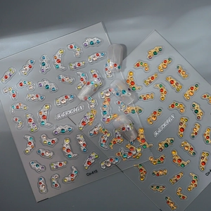 Detail view of 3D rhinestone nail stickers with gold and silver base and colorful gems
