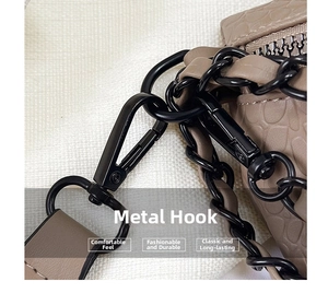 Detail of matte black metal hardware hook and chain on crocodile texture crossbody bag