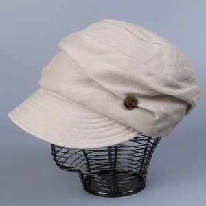 Close-up of beige linen newsboy cap featuring pleated texture and brown wooden button