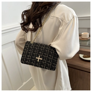 Detail of black tweed crossbody bag featuring gold chain strap and metallic lock buckle