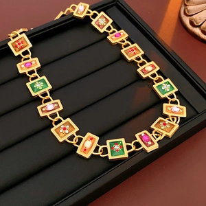 Macro view of vintage gold necklace featuring colorful enamel links and inlaid gems