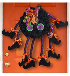 Close-up of Halloween spider door wreath with purple striped legs and witch boots decoration