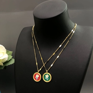 Colliers fleurs avec pendentifs rouge et vert présentés sur un buste de mannequin
