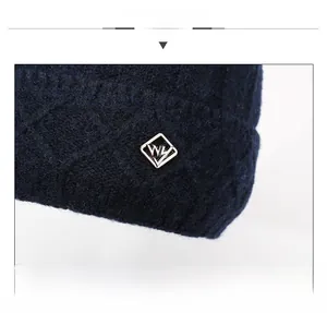 Macro shot of navy knit beanie featuring textured diamond patterns and a silver metal logo