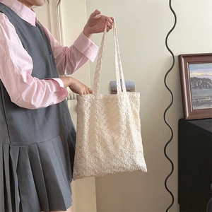 Detailed close-up of white floral lace tote bag with delicate hollowed-out mesh pattern