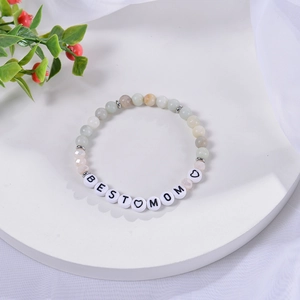 Detailed shot of Best Mom beaded bracelet with heart charm on a white display stand