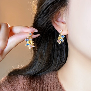 Elegant gold-tone horse pendant earrings with colorful rhinestones on model's ear