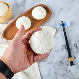 Squeezable 8cm PU slow rebound steamed bun toy held over a traditional bamboo steamer
