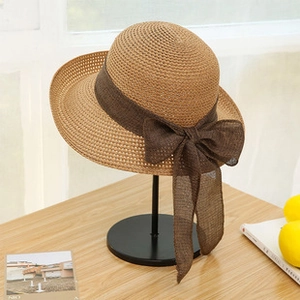 Detailed close-up of a women's foldable straw sun hat featuring a brown ribbon bow