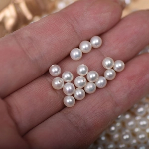 Detail of 4mm white freshwater pearls held by hand to show size and natural luster