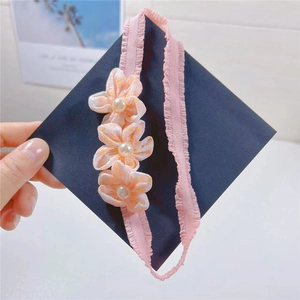 Detail of pink fabric flowers with faux pearls on a baby headband held by hand