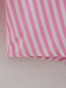Detailed macro shot of pink striped fabric texture and neat stitching of the shirt set