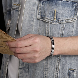 Retro silver skull steel bracelet for men with woven texture on a casual denim background