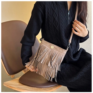 Detail of light brown suede crossbody bag featuring stylish fringe accents and smooth texture