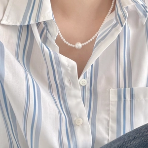 Detail of elegant pearl necklace featuring a large center pearl on a female model neck