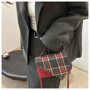 Detail of vintage plaid crossbody bag with red leather trim and metal edge decoration