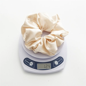Close-up of a champagne satin scrunchie weighing 12.4g on a digital scale
