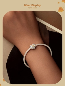 Vue détaillée du bracelet en maille argentée avec breloque cœur et détails de feuilles dorées