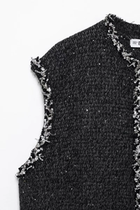 Gros plan sur une robe sans manches en tweed noir avec sequins et bordures tissées