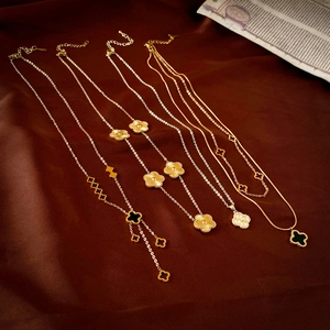 Vue à plat de colliers en or trèfle sur soie marron avec journal vintage