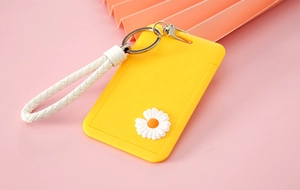 Detail of yellow card holder with white daisy and woven wrist strap on pink background