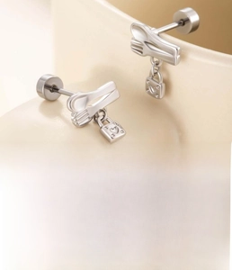 Detailed view of silver cutlery-shaped stud earrings with heart lock charms and flat backs