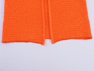 Detailaufnahme des Saums aus leuchtend orangefarbenem Strick mit Pailletten